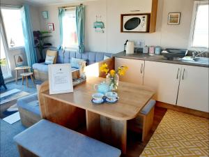 a living room with a table and a kitchen at Bliss Beach Lodge in Bembridge