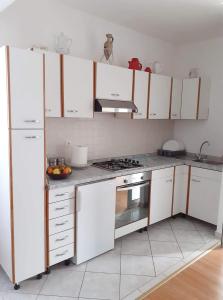eine Küche mit weißen Schränken und einem Herd mit Backofen in der Unterkunft Apartmani Brkljača 2 -Ive in Biograd na Moru