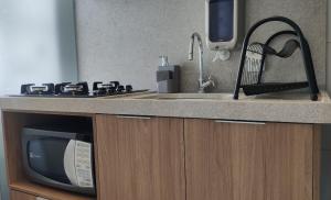 a kitchen counter with a sink and a microwave at JTR | Ar na Sala, Localização Privilegiada+Piscina in Maceió