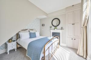a white bedroom with a bed and a fireplace at Luxury Georgian Townhouse Moments from the Harbour in Looe