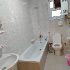 a bathroom with a tub and a toilet and a sink at Afnan Guest- Rehab City in Burg el-Ḥudûd +27 photos