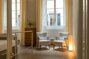 a bedroom with two chairs and a bed and windows at Casa G. Firenze in Florence