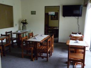 una sala da pranzo con tavoli, sedie e TV a schermo piatto di Hotel de la Avenida a Chillán
