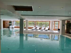 a large swimming pool in a building with chairs at Garden apartment SPA&Pool in Vallorcine