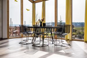 een tafel en stoelen in een kamer met ramen bij Ruhige Ferienwohnung mit Panoramablick in Ingoldingen