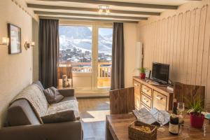 a living room with a couch a table and a television at Lac Blanc Appartements VTI in Val Thorens