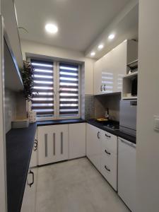 a kitchen with white cabinets and a large window at Apartament Wrocław Borowska in Wrocław