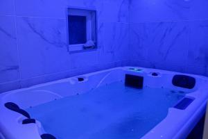 La salle de bains est pourvue d'une grande baignoire avec un éclairage bleu. dans l'établissement Spa de la Nacre, L'étape Repos, à Andeville