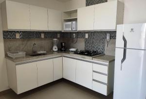 a kitchen with white cabinets and a white refrigerator at Areias do Mar ! 2 Quartos Vista Mar e Varanda A204 in Barra de São Miguel