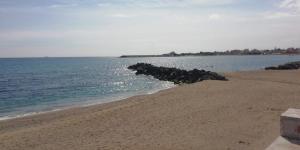 una playa con una roca saliendo del agua en CASA del MORO en Giardini Naxos