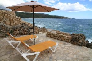 two chairs and an umbrella next to the ocean at Bella Costa Lux in Dobra Voda