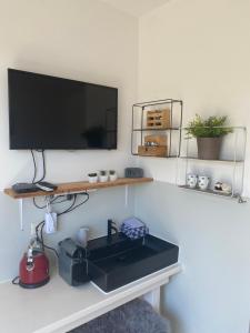 a kitchen with a sink and a tv on a wall at Logies Boszicht Texel in De Koog