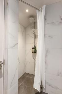 La salle de bains est pourvue d'une douche et de murs en marbre blanc. dans l'établissement Period Henley 2 bed apt with parking for 1 car, à Henley-on-Thames