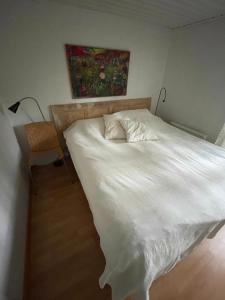 Un dormitorio con una cama blanca con una silla y una pintura en Havsnära paradis en Yngsjö