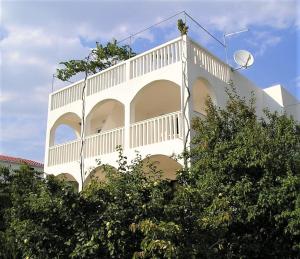 a white building with a balcony on top of trees at Apartment Nataša- Apt.1 in Trogir