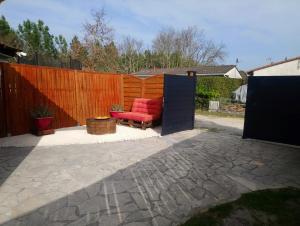une terrasse avec une chaise rouge et une clôture dans l'établissement Bassin d'Arcachon - studio Ares -, à Arès