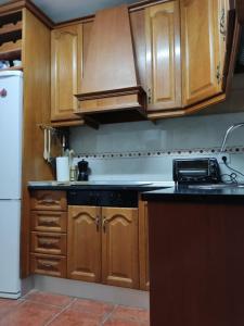cocina con armarios de madera y encimera negra en Alojamiento CHAYGRAM en Jaén