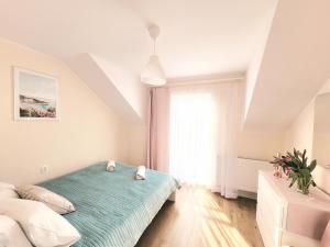 a white bedroom with a bed and a window at Domki Apartamentowe ITALIA in Karwia