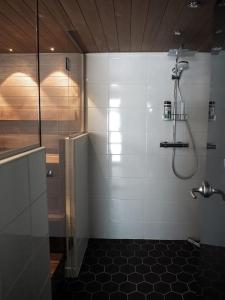baño con ducha y suelo de baldosa negra en Kalliorinne, en Kuusamo