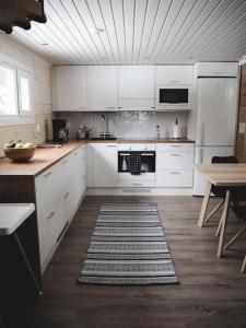 Il comprend une cuisine avec des placards blancs et du parquet. dans l'établissement Kalliorinne, à Kuusamo