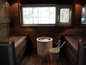 a small bathroom with a trash can and a window at Kalliorinne in Kuusamo