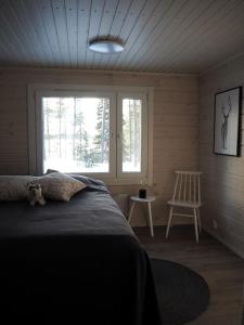 a bedroom with a bed and a chair and a window at Kalliorinne in Kuusamo