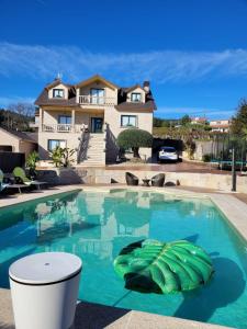 a swimming pool in front of a house at Casa A Boleriña 2 in Combarro