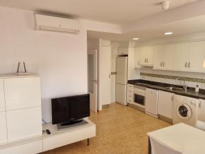 オリーバにあるHELLO OLIVA BEACH Anaの白いキャビネットと薄型テレビ付きのキッチンが備わります。