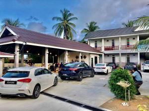 two cars parked in a parking lot in front of a building at Lakse Inn Homestay in Kampong Pengkalan Maras