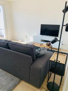 a living room with a couch and a desk with a television at Wohnung Skandi-Home ruhige Lage NEU - Düsseldorf Nord in Düsseldorf