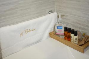 a bathroom sign on a bed with a bottle of alcohol at Casa A Boleriña 2 in Combarro