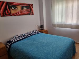 um quarto com uma cama azul com um quadro na parede em HELLO OLIVA BEACH Ana em Oliva