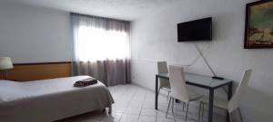 カジャオ・サルバヘにあるStudio Barandasのベッド、デスク、テレビが備わるホテルルームです。