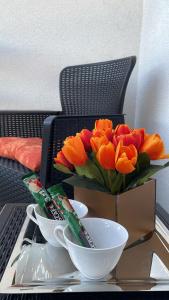 un jarrón de tulipanes naranjas sentado en una mesa con tazones en Apartman Venera en Sombor