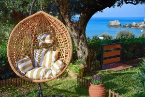 een rieten stoel in het gras onder een boom bij Ionian Senses - Corfu, Glyfada Menigos Resort in Glyfada