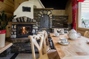 einen Holztisch mit Stühlen und einen Steinkamin in der Unterkunft udanypobyt Domki Przy Potoku in Zakopane