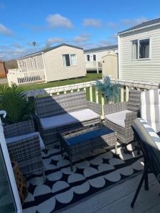 Un patio con sillas y una mesa en una terraza. en Tattershall Lakes Caravan Ezees Holiday Retreat, en Tattershall