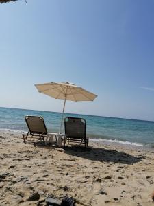 two chairs and an umbrella on the beach at Crystal Blue Apartments in Nea Kalikratia