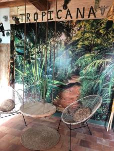 2 sillas y una mesa frente a un mural en Les pieds dans l'eau TROPICANA, en Corné