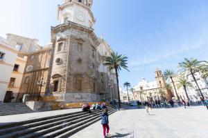 a girl standing in front of a building with a clock tower at ENTREARCOS in Cádiz