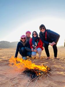 un grupo de personas de pie alrededor de un fuego en la playa en wadi rum land mars en Wadi Rum