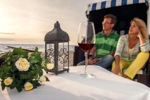 Un uomo e una donna seduti a un tavolo con un bicchiere di vino di Hotel Blinkfüer a Dierhagen