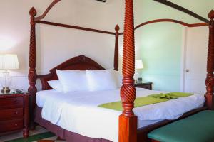 a bedroom with a four poster bed with a wooden frame at Hotel Victoriano in San Juan del Sur
