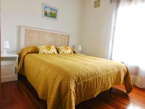 a bedroom with a bed with a yellow comforter at La Pilarcita Centro in Fuenmayor
