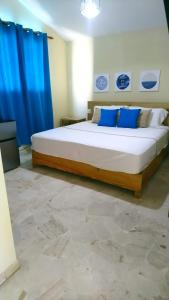 a bedroom with a large bed with blue curtains at Verde Bonavita in Santiago de los Caballeros
