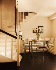 a dining room with a table and chairs and a staircase at Pied A Terre - Tuileries in Paris