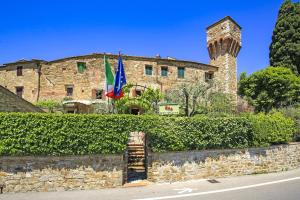 un bâtiment en pierre avec deux drapeaux devant lui dans l'établissement Apartment in B&B Del Giglio, à San Donato in Poggio