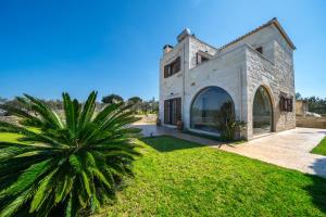 - une vue sur l'extérieur d'une maison en pierre avec un palmier dans l'établissement FOS residence - ΦΩΣ ,luxury villa, à La Canée