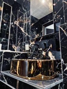 a bathroom with a gold sink in a black marble wall at thesstay Attica downtown boutique apartment in Thessaloniki
