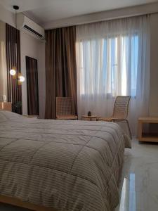 a bedroom with a large bed and two chairs at thesstay Attica downtown boutique apartment in Thessaloniki